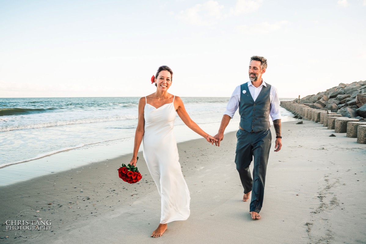  Fort Fisher Wedding Photographers - Ft Fisher Wedding Photography  -Bride and groon walking along the beach at   Fort Fisher North Carolina -  Wedding Photography - Wedding Ideas - Bride - Groom - Wedding Dress - Chris Lang Photography- Popular wedding location - 