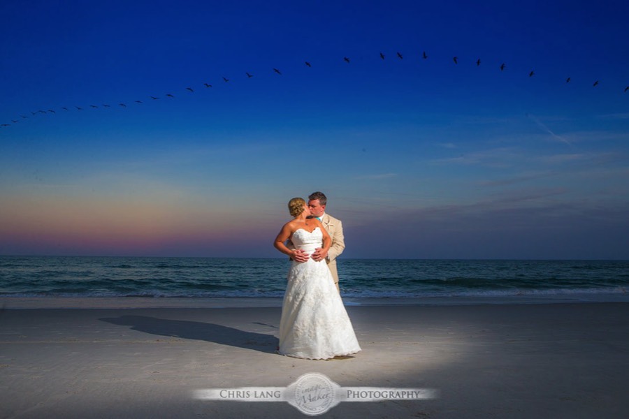 Wrightsville-Beach-Wedding-Photographers-Picture-of-bride-groom-on the beach at sunset with pelicans flying overhead