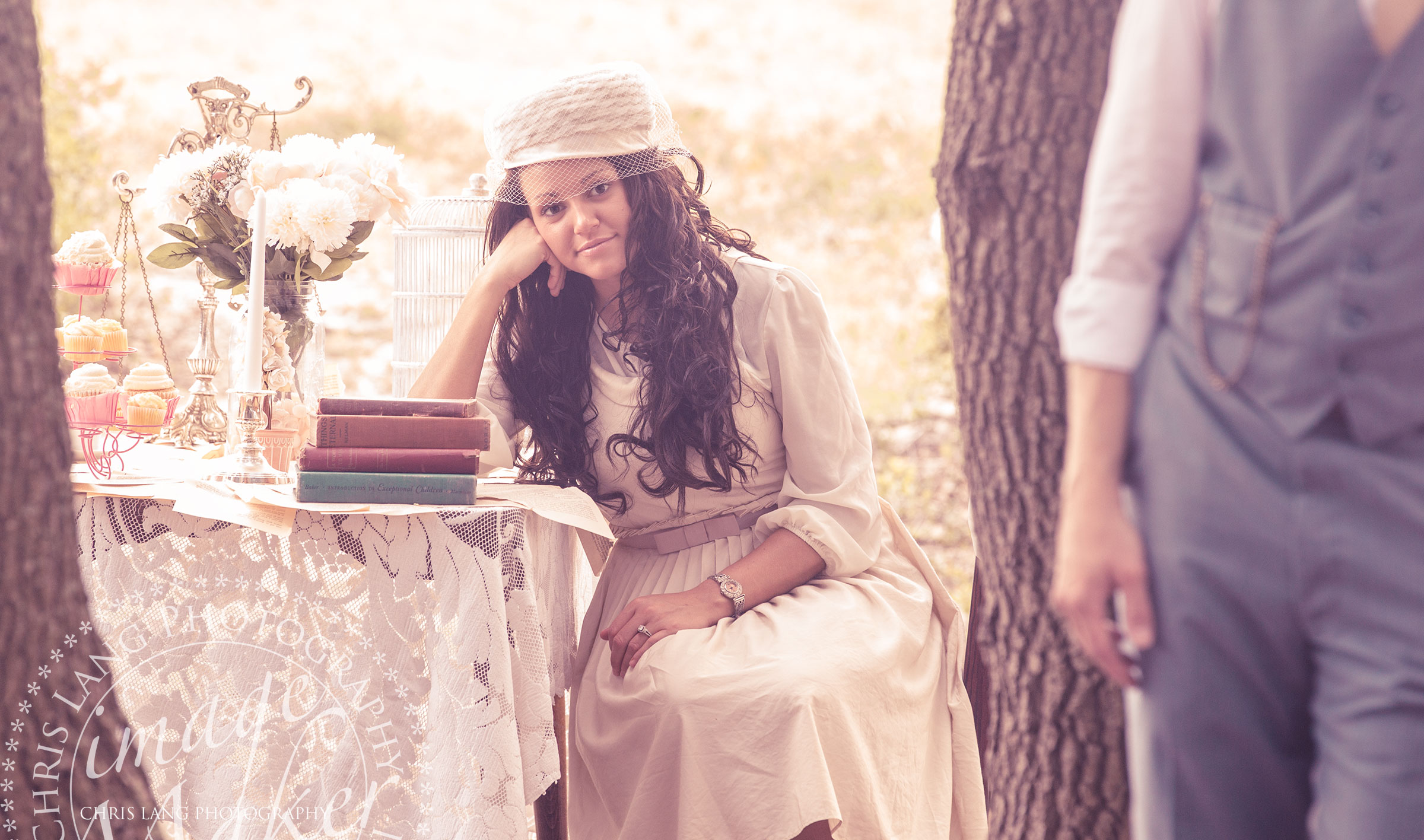 Vintage Style engagment picture of a couple sitting at an outdoor table decoratred with vintage props at Fort Fisher