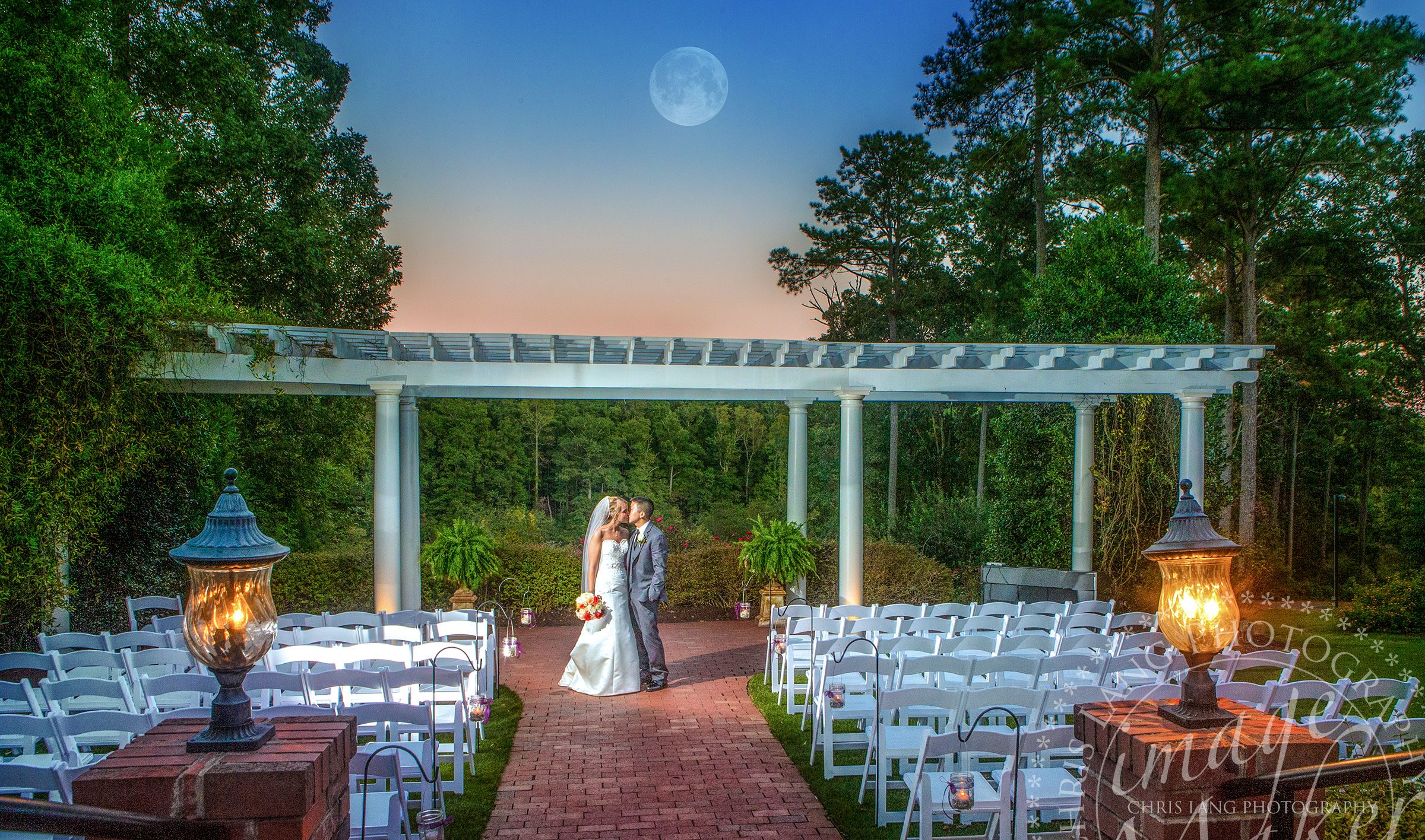 Wedding picture of a bride and grom kissing under a moon at twilight.  North Carolina Wedding Photographers.