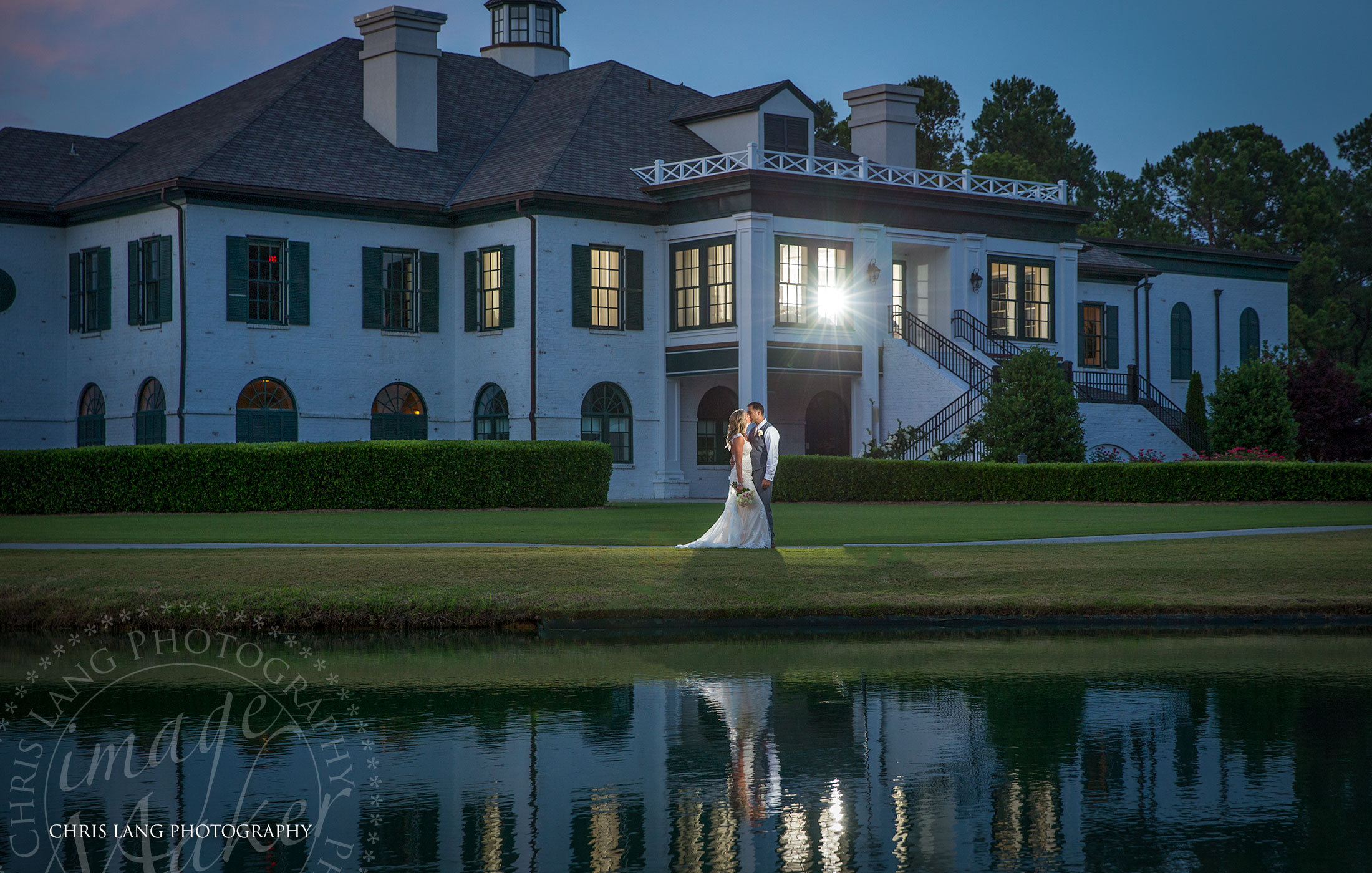 Porters Neck Country Club Weddings -Image of wedding couple in front of the Porters Neck Country Club overlloking the lake on the golf course.