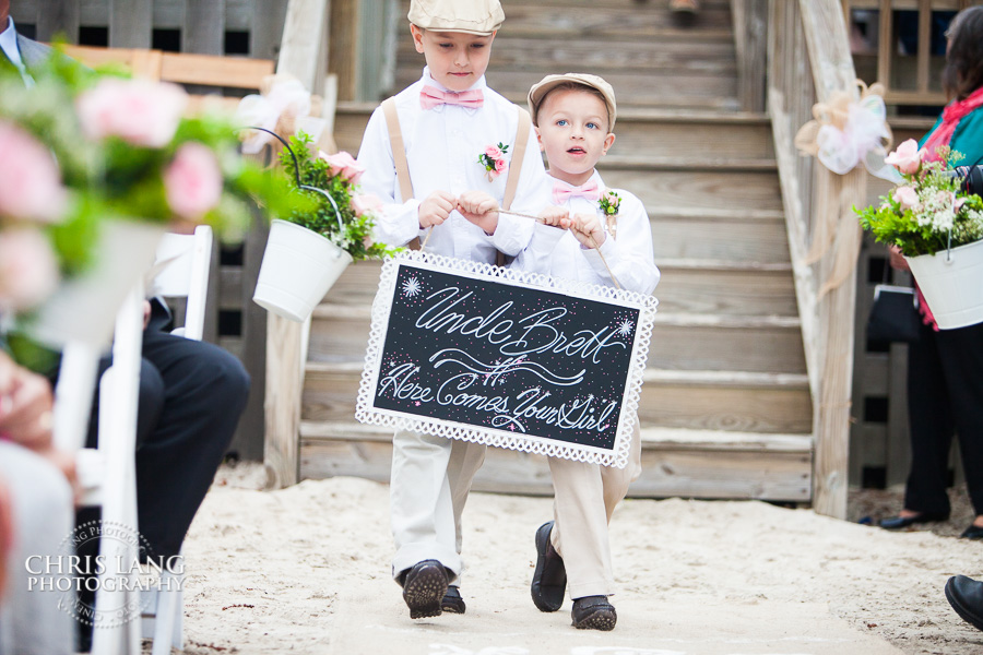 Sign Bearer walkin down the isle of a River Landing River Lodge, Wallace NC - Wedding Photography