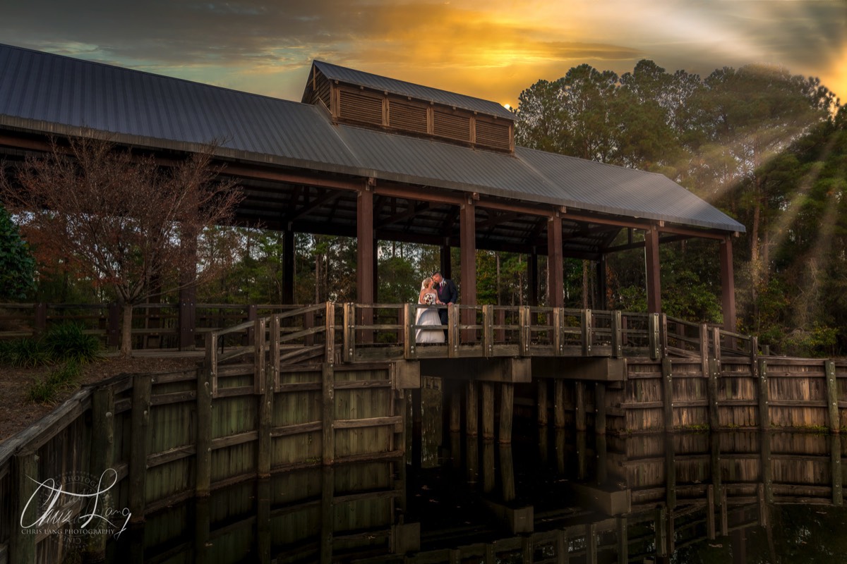 bride & groom on the covered bridge at river landnig golf course - 