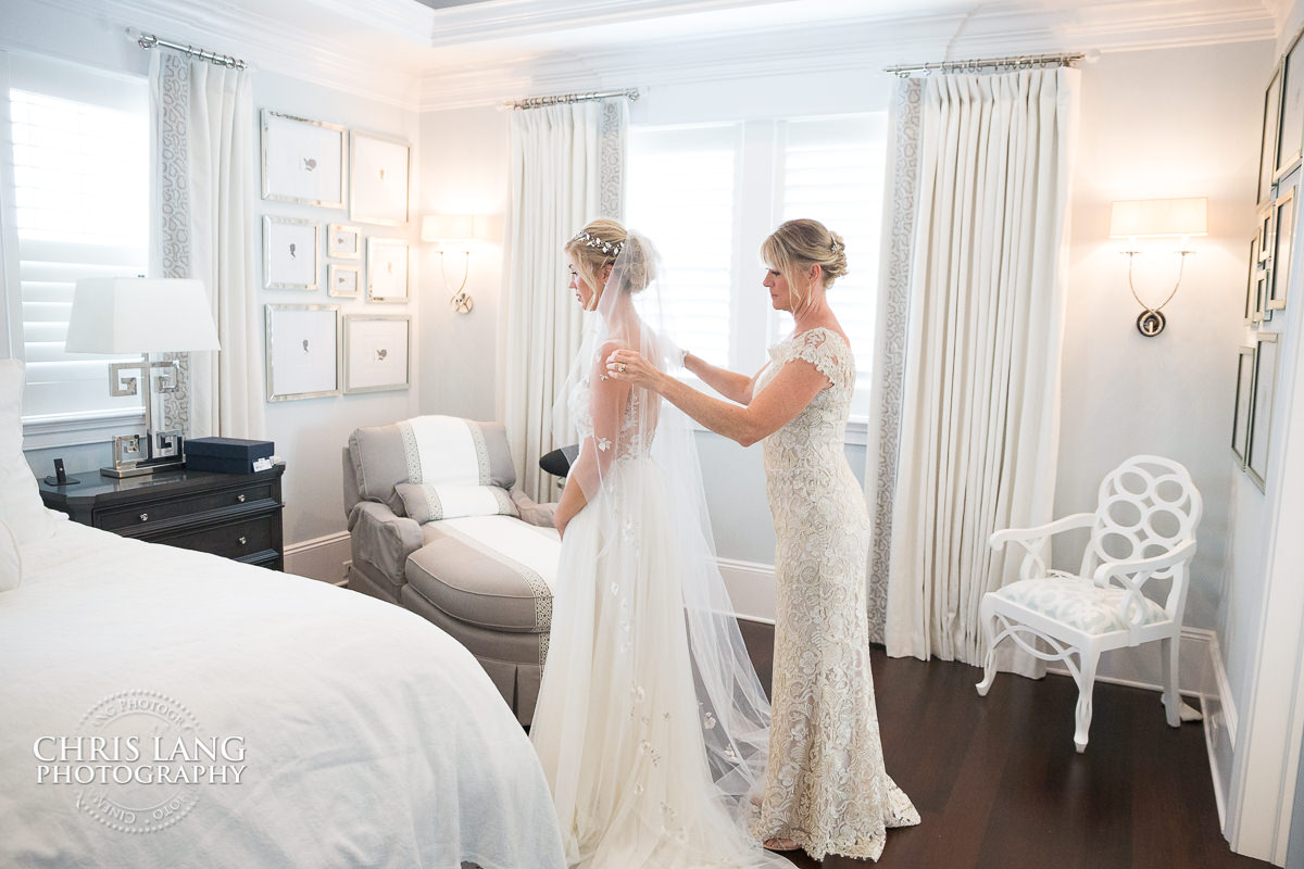 mother of bride puttinf the final touches of the brides wedding dress - wilmington weddings