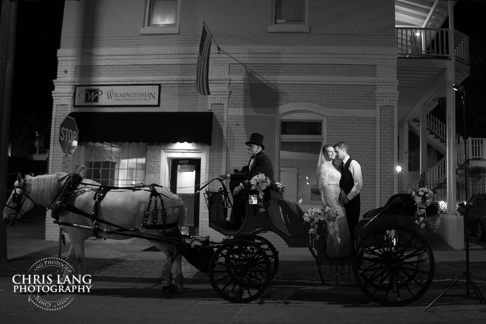 photo of bride and groom riding in horse and carriage -  Wilmington wedding photography - night wedding photography - evening wedding photos- bride - groom -  night time wedding photo ideas - low light wedding photography
