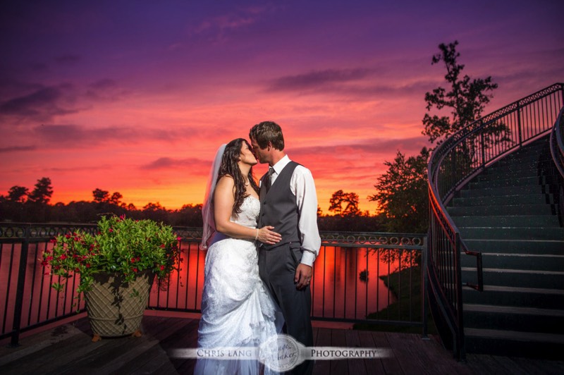 A wedding picture of a couple kissing in front if a majestic sunset with orange and red skies.  Wilmington NC Wedding Photography