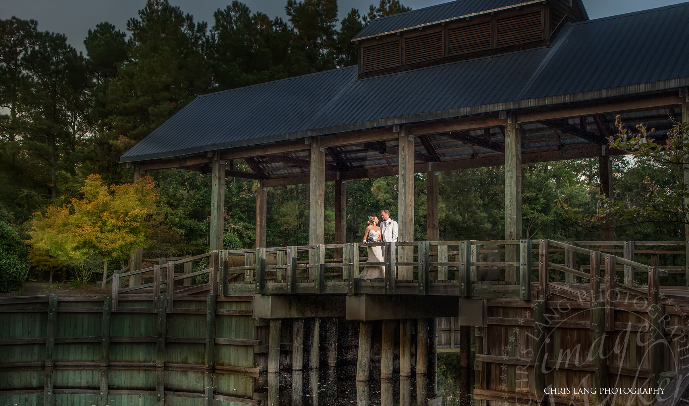 Wedding picture of a groom about to put a ring on hte brides finger as they are both smiling while looking at the ring. Wilmington NC Wedding Photographers