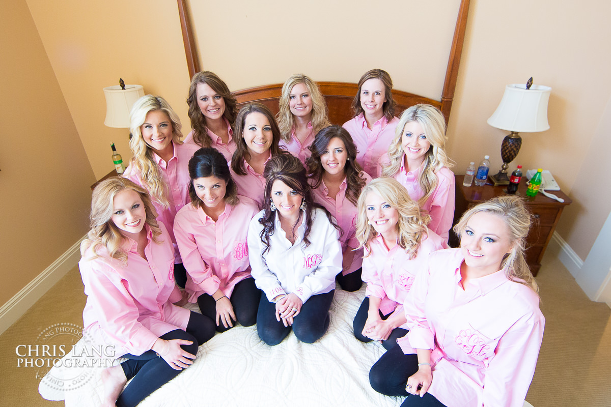 bridesmaids sitting on bed - monogram shirts - bridal party - pre wedding photos - wedding photo ideas - getting ready wedding pictures - bride - groom - wedding dress - wedding detail photos - river landing weddings