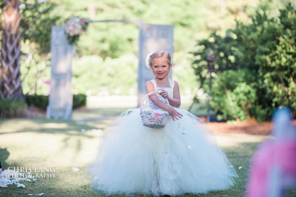 flower girl walking down the isle during a outdoor Southern wedding - Wrightsville Manor Weddings - Wilmington NC - Wedding Photography 